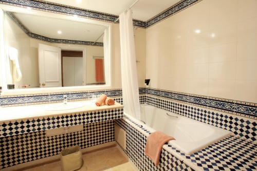 甘达坞伊港Sentido Bellevue Park的带浴缸、水槽和镜子的浴室