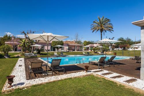 塔维拉Quinta de Santa Margarida - Charm Country House的庭院内带椅子和遮阳伞的游泳池
