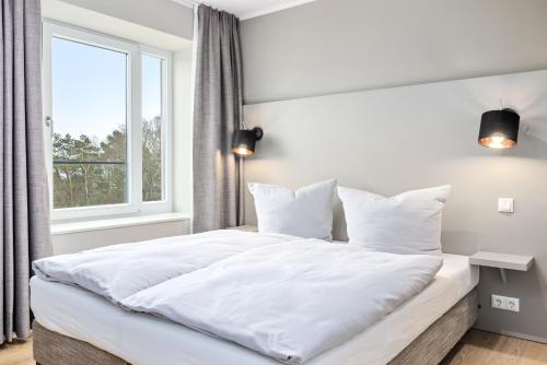 宾茨Strandresidenzen Strandresidenzen Haus Dänholm 3 1的卧室内的一张白色床,设有窗户
