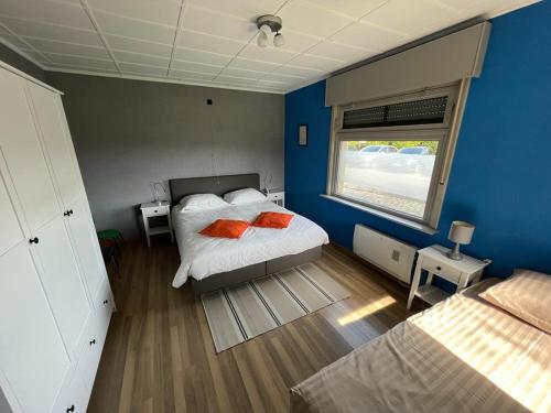 布列登Huize Liesanne的一间卧室拥有蓝色的墙壁,配有一张带橙色枕头的床。
