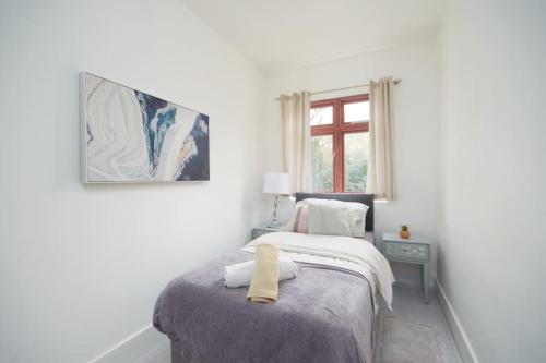 Winchmore HillLarge London home with Free parking的白色卧室,床上有黄毛巾
