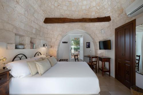 洛科罗通多阿普里勒马塞里亚酒店的卧室配有白色的床和石墙