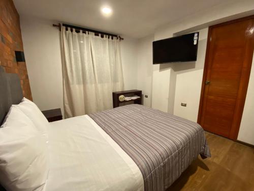 帕卡斯马约Hotel Central Pacasmayo的一间卧室配有一张床和一台平面电视