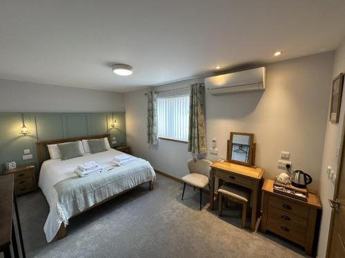 奥克尼Royal Oak Guesthouse的一间卧室配有一张床、一张书桌和一面镜子