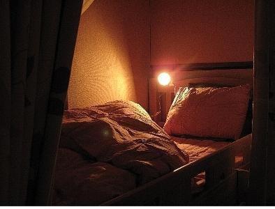 奈良奈良背包客宾馆的卧室配有一张墙壁上灯床。