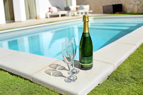 莫甘Escape to paradise luxury Poolvilla with ocieanview near Amadores的一瓶葡萄酒和一杯游泳池旁的玻璃