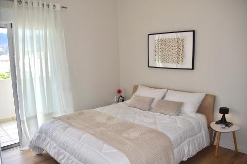 卡拉马塔KAPA Central Apartment的卧室配有一张白色床,墙上挂着一幅画