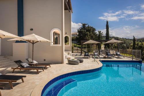 费斯卡尔德宏Luxury Villa Karmaniolos Fiskardo Kefalonia的房屋旁的游泳池配有椅子和遮阳伞