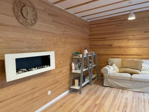 吕内维勒L'écolodge de Laeti的客厅设有木墙、电视和沙发