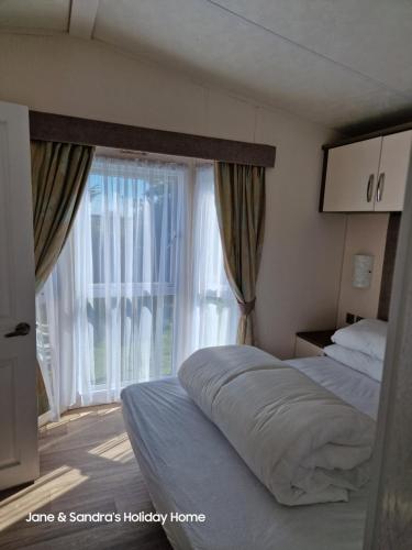 Jaywick SandsPRIVATELY OWNED Stunning Caravan Seawick Holiday Park St Osyth的一间卧室设有一张床和一个大窗户
