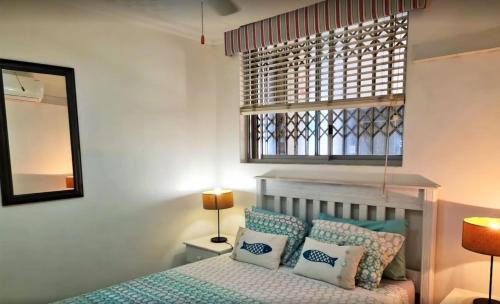 马盖特Santorini Unit RR的卧室配有带枕头的床铺和窗户。