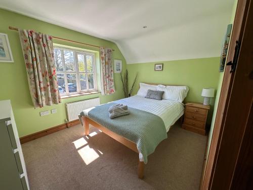 伍德布里奇Rockhopper Cottage, Waldringfield的绿色卧室设有床和窗户