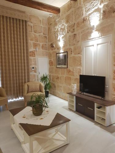 梅利哈Tal-Kampjin的一间带电视和石墙的客厅