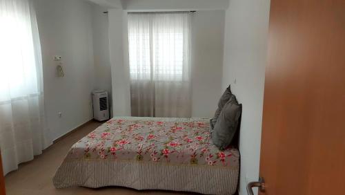 明德卢Apartamento F3, Lazareto - Mindelo的一间卧室配有一张带鲜花毯子的床和窗户。