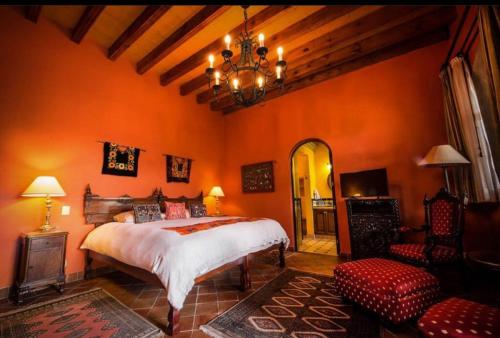 圣米格尔-德阿连德Casa Don Pascual Hotel Boutique Sweet Home的一间卧室设有橙色的墙壁、一张床和一个吊灯。