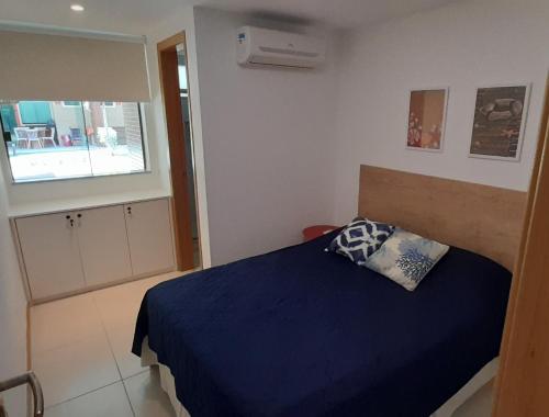 伊塔齐米林Village Pé na Areia - Itacimirim的一间卧室设有蓝色的床和窗户。
