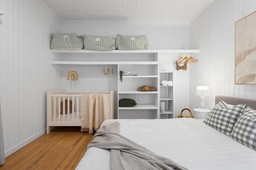黄金海岸Rigi on Currumbin Beach的一间白色卧室,配有一张床和一张婴儿床