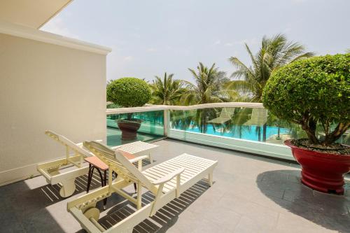 美奈海联海滩高尔夫度假酒店的一个带白色椅子的阳台和一个游泳池