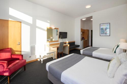 普纳凯基Scenic Hotel Punakaiki的酒店客房,设有两张床和一张红色椅子