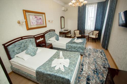 Khodzha-AkhrarHotel Asia Samarkand的酒店客房带两张床和一张桌子以及椅子。
