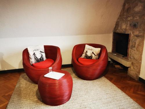 La Geneytouseles bois de saint Auvent的带壁炉的客房内的2把红色椅子