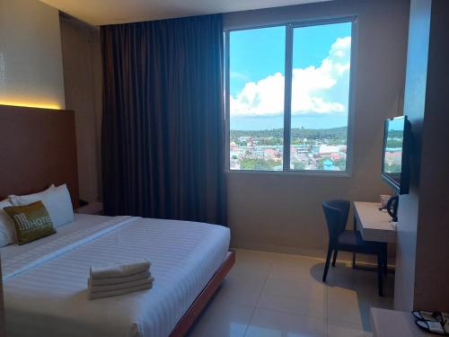 巴淡岛中心OS Hotel Airport Batam的配有一张床、一张书桌和一扇窗户的酒店客房