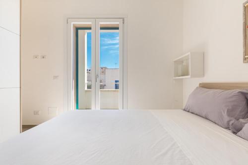 CampomarinoResidence Amida by BarbarHouse的白色的卧室设有一张白色大床和一个窗户。