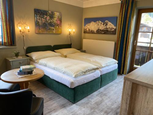 基茨比厄尔Hotel Edelweiss Kitzbühel的一间带一张大床的卧室,位于带桌子的房间
