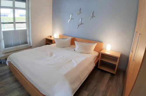布雷格Hafenglück的卧室配有一张铺有白色床单的床,墙上有鸟儿