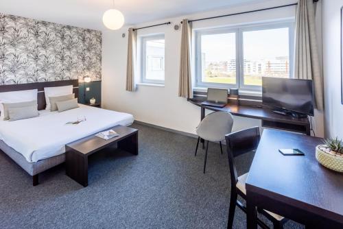 图卢兹Nemea Appart Hotel Toulouse Aéroport的配有一张床和一张书桌的酒店客房
