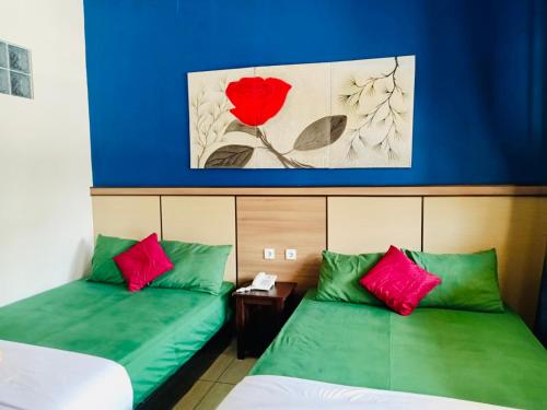 庞岸达兰庞岸达兰阿伦旅馆的配有绿色和红色枕头的客房内的两张床