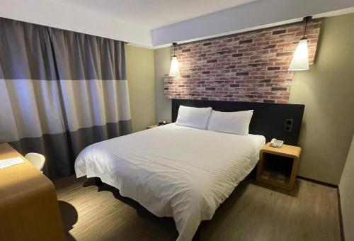 台北苓旅中山馆-Lininn ZhongShan的酒店客房,设有床铺和砖墙