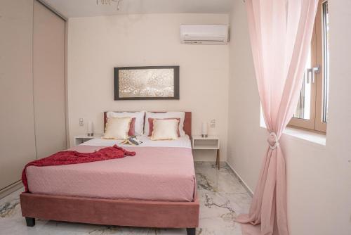 Marie Claire Luxury Maisonette的一间卧室配有一张带粉色床单的床和一扇窗户。