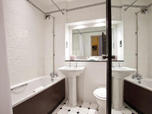 斯陶尔波特Stourport Manor Hotel的一间带两个盥洗盆、浴缸和卫生间的浴室