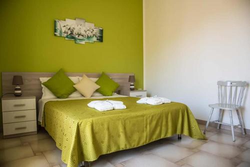 兰佩杜萨Blu Mare Lampedusa Bed And Breakfast的一间卧室配有一张带绿色墙壁的床和一把椅子