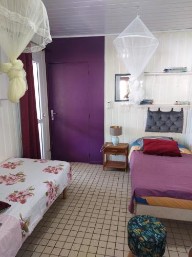 波尔兰特LES GÎTES DU DOMAINE DE PETITE-ANSE的一间卧室设有两张床和紫色墙壁