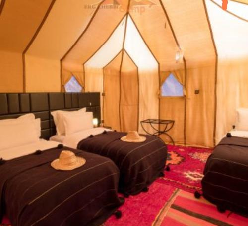 梅尔祖卡Merzouga Luxury Tented Camp的帐篷内的两张床,配有帽子