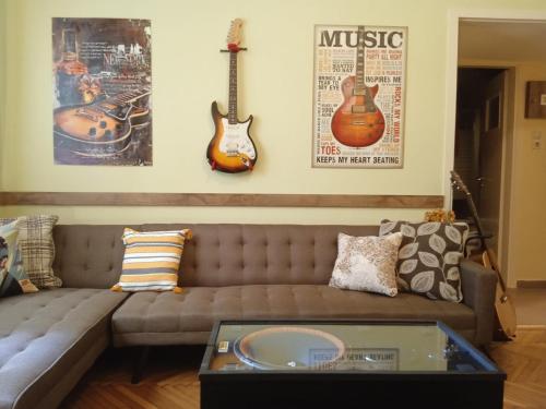 雅典Still got the blues的客厅配有沙发和墙上的两把吉他