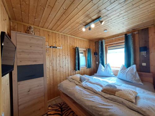HöfenChalet Panorama Tirol的木制客房的一张床位,设有窗户