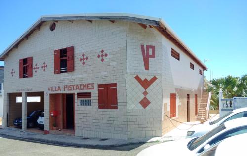 大博格Villa Pistaches的一座白色的小砖砌建筑,设有红色的门窗