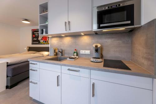 诺德奈Haus Andersen Apartment EINS的厨房配有白色橱柜、水槽和床。