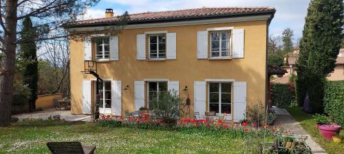 VourlesChambre d'hôte chez Florence的黄色的房子,有白色的窗户和红色的鲜花