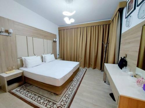 沙迦1BR Warm and comfortable APT的卧室配有一张白色的大床和两张桌子