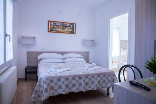 里乔内Affittacamere Ceccarini的白色卧室配有一张带桌子的床