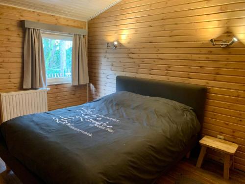 拉纳肯Het Zenhuisje的卧室配有木墙内的一张床