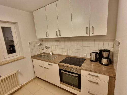 卡尔斯特Viktoria's Wohnung in Kaarst的厨房配有白色橱柜、炉灶和水槽。