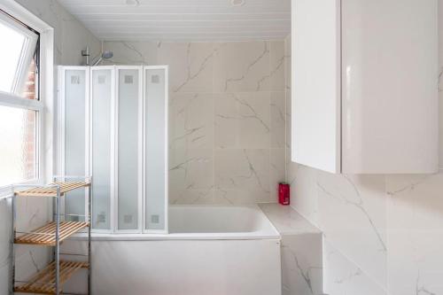 沃金Maybury Maison的白色的浴室设有浴缸和白色橱柜。