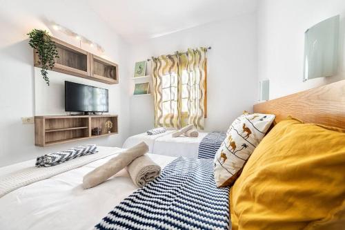 圣巴托洛梅BUNGALOWS LOS ARCOS 77的一间卧室设有两张床,墙上配有电视。