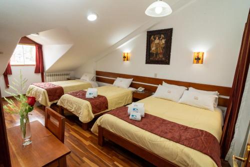 库斯科Kenamari Hotel Cusco的酒店客房设有两张床和一张桌子。