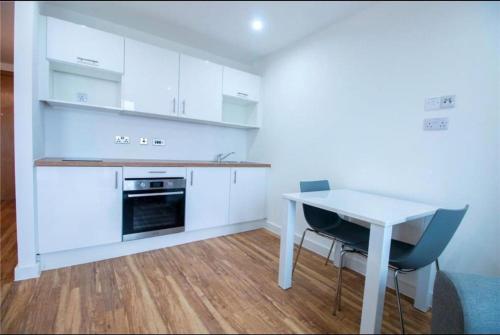 曼彻斯特Luxury Apartment near Media City的厨房配有白色橱柜和白色的桌椅